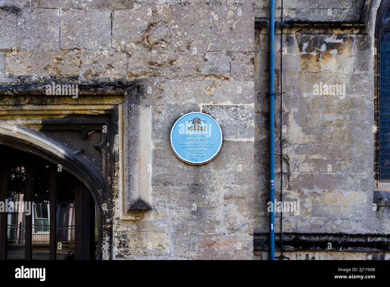 Plaque bleue sur le mur de l'église Saint-Pierre du 15th siècle commémorant l'ordination de Thomas Wolsey en 1498, High Street, Marlborough, Wiltshire Banque D'Images