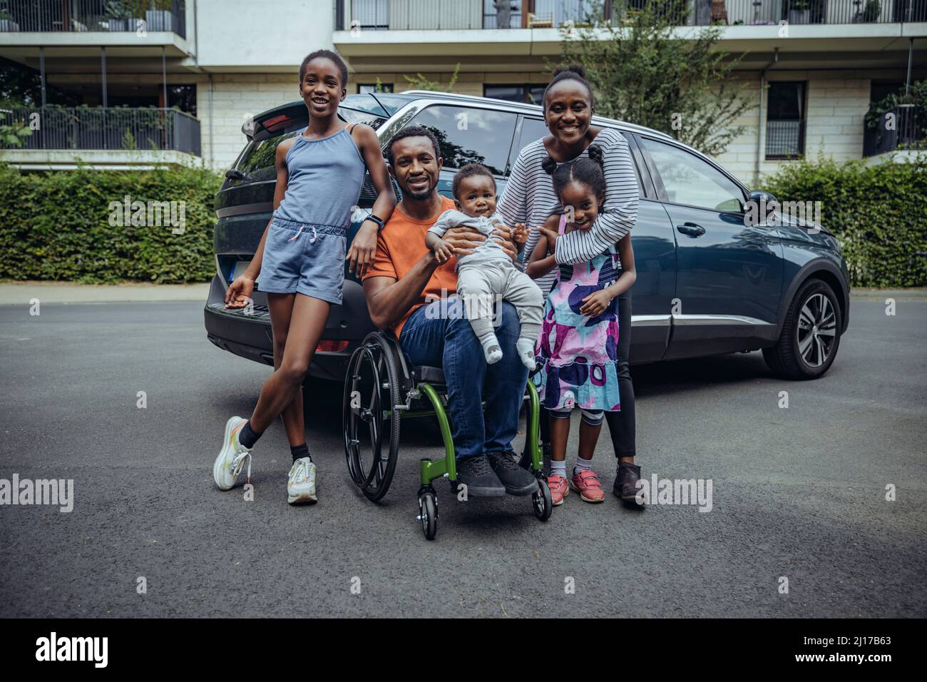 Père assis en fauteuil roulant par la famille sur la route Banque D'Images
