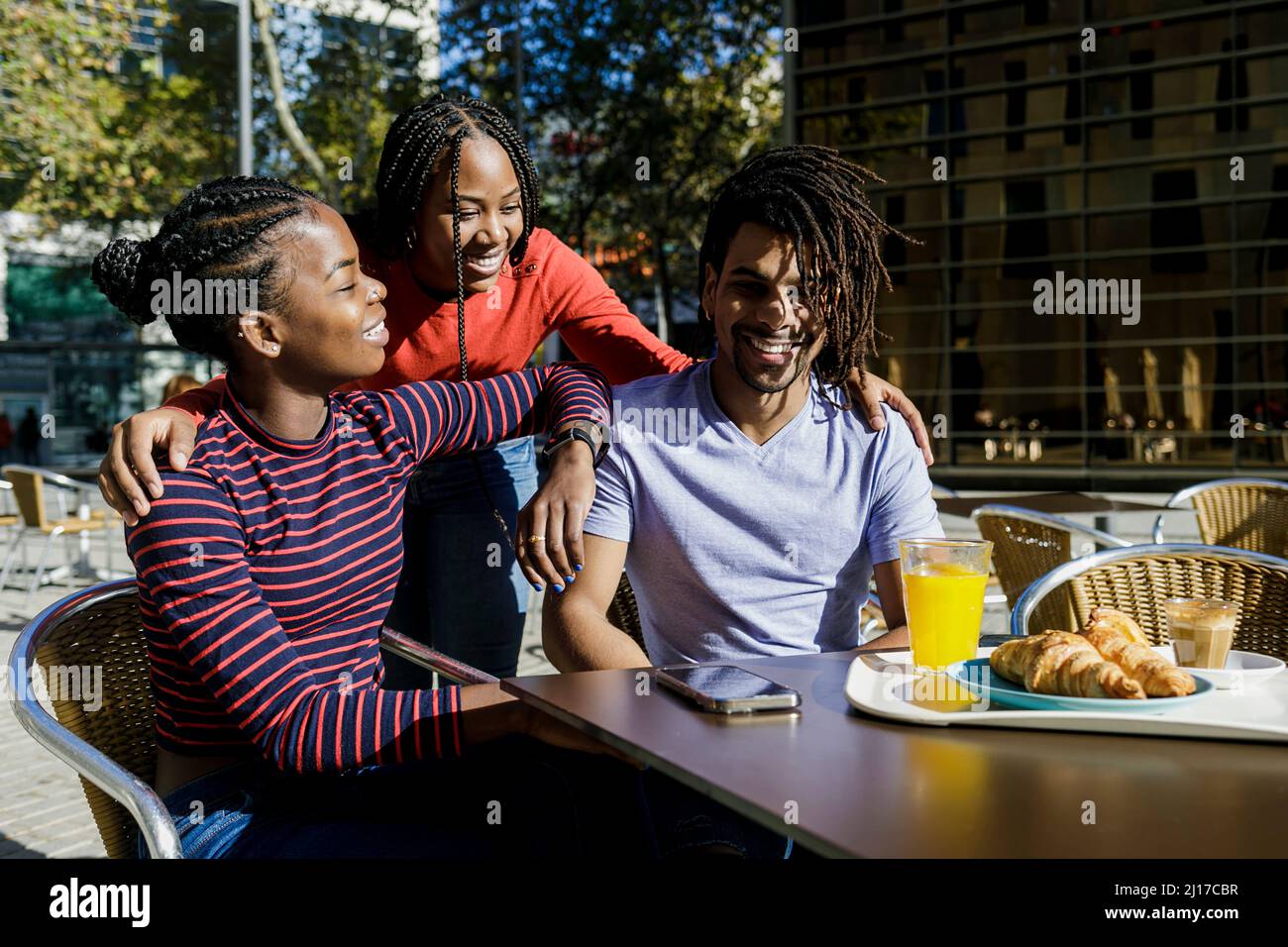 Jeune femme souriante discutant avec des amis au café-terrasse Banque D'Images