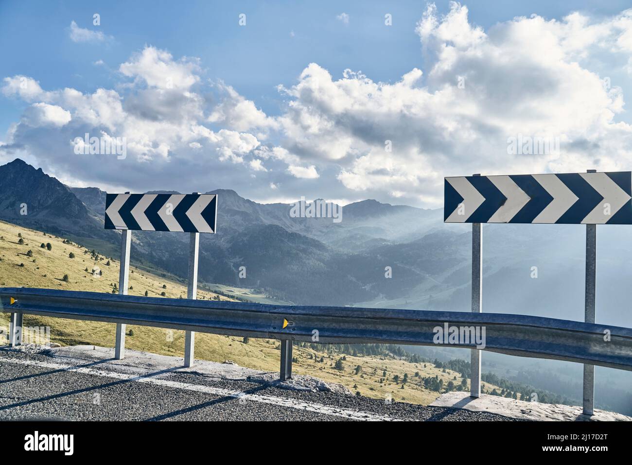 Route de montagne avec flèche de circulation le jour ensoleillé Banque D'Images