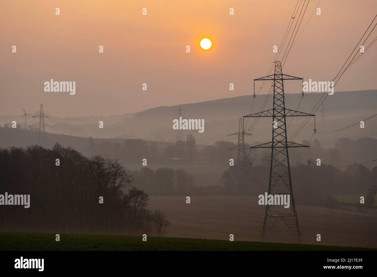 Ledgerwood aux frontières écossaises, Royaume-Uni. 23rd mars 2022. Engery, électricité, électricité. Le soleil se lève un autre jour de prix élevés de l'énergie alors que le coût de la vie continue d'augmenter. La transition vers l'énergie verte est une priorité, mais aussi l'équilibre entre la réduction des coûts de l'énergie actuellement élevée en raison de la pandémie de cavid et de la guerre actuelle en Ukraine et des sanctions contre la Russie. La vue est de pylônes d'électricité et une distance éolienne que le soleil se lève près de Ledgerwood dans les frontières écossaises. Crédit : phil wilkinson/Alay Live News Banque D'Images