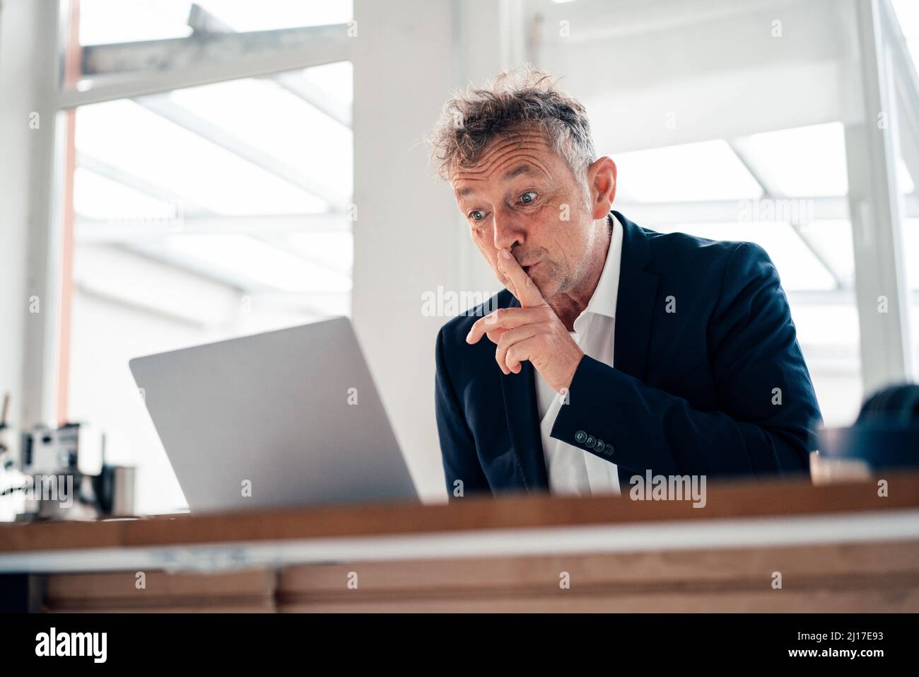 Homme d'affaires expérimenté faisant un geste de silence sur les appels vidéo via un ordinateur portable Banque D'Images