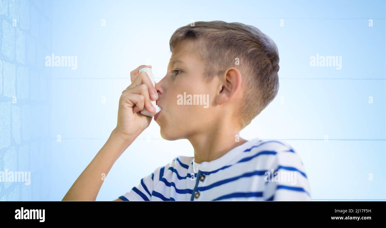 Garçon caucasien utilisant un inhalateur d'asthme contre le mur de brique et le fond bleu Banque D'Images
