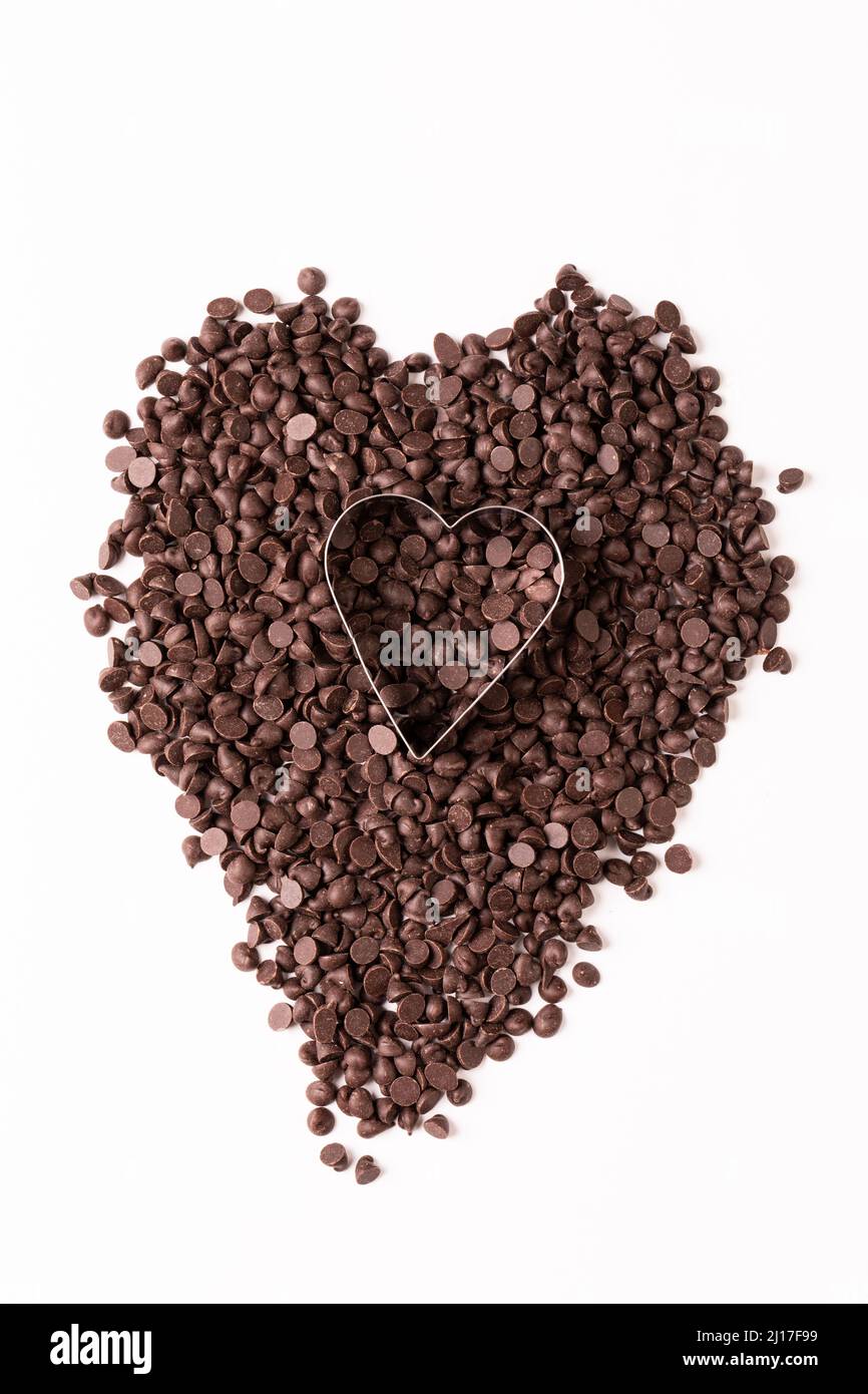Vue en hauteur du couteau à pâtisserie en forme de cœur sur des copeaux de chocolat sur fond blanc Banque D'Images