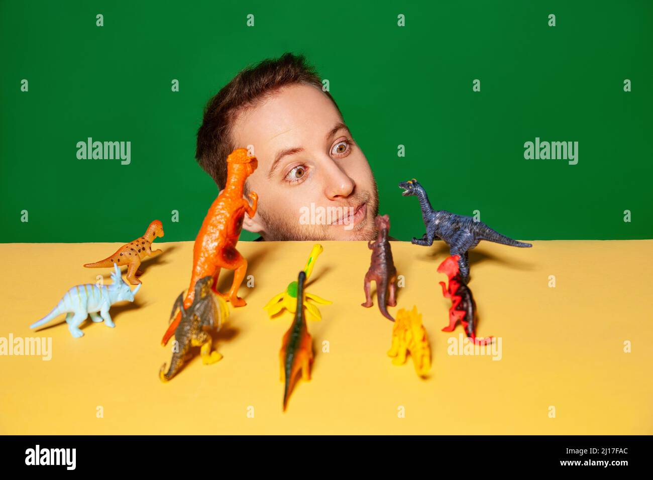 Jeune homme avec figurines de dinosaure sur fond vert Banque D'Images