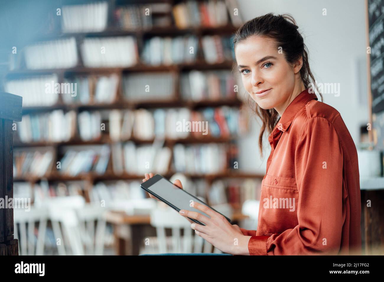 Femme souriante avec un ordinateur tablette dans une hache à café Banque D'Images