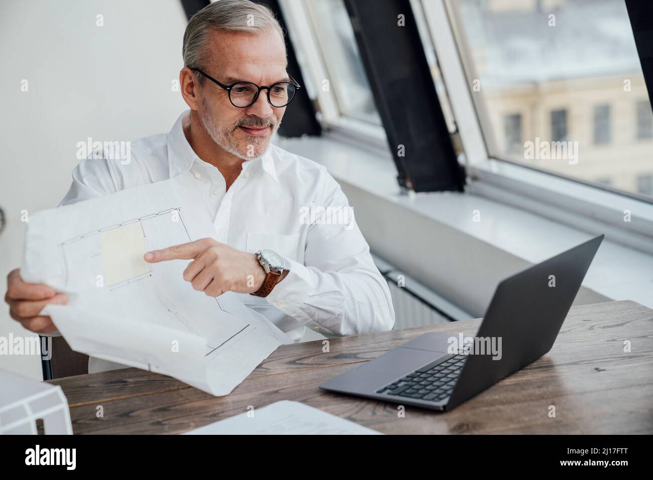 Architecte avec document sur appel vidéo sur ordinateur portable sur le lieu de travail Banque D'Images