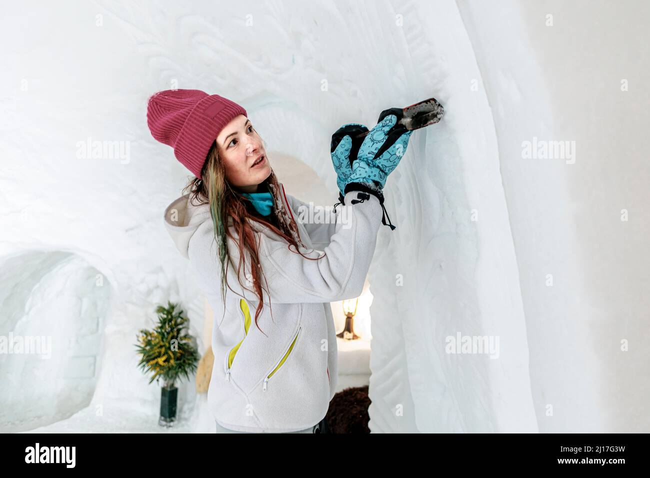 Femme avec chapeau en tricot sculptant le motif sur la neige dans l'igloo Banque D'Images