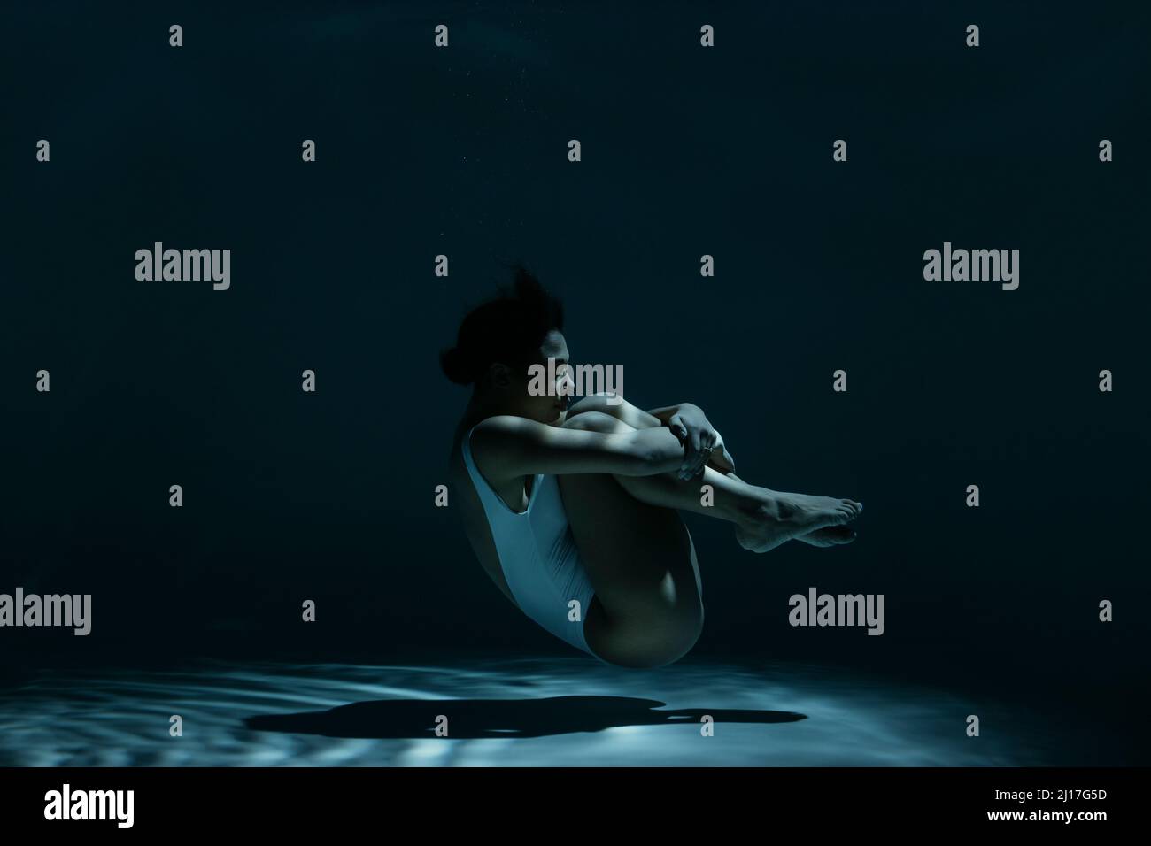 Femme en position fœtale natation sous l'eau Banque D'Images
