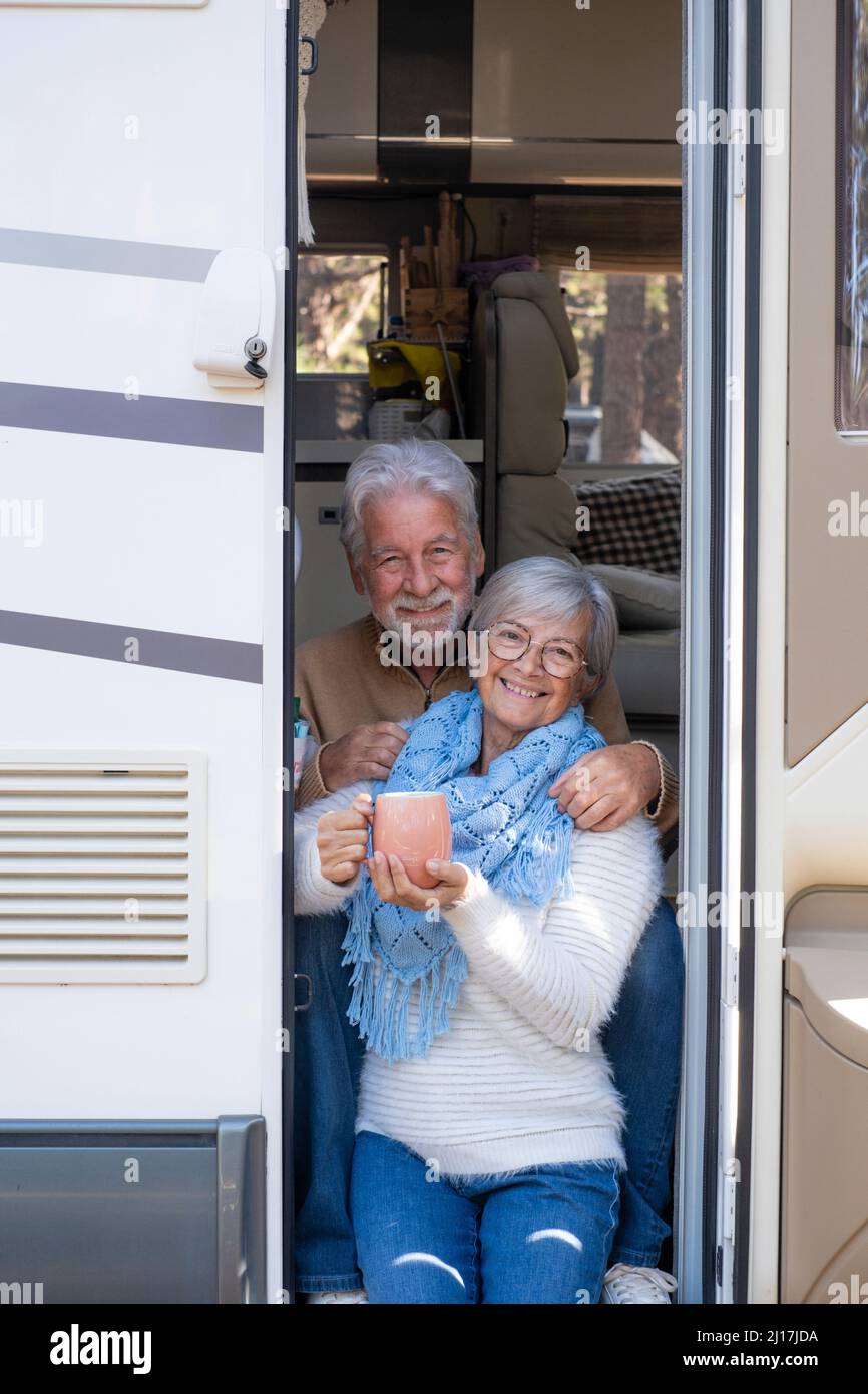 Couple senior heureux avec une tasse de café assis à la porte de la maison de moteur Banque D'Images