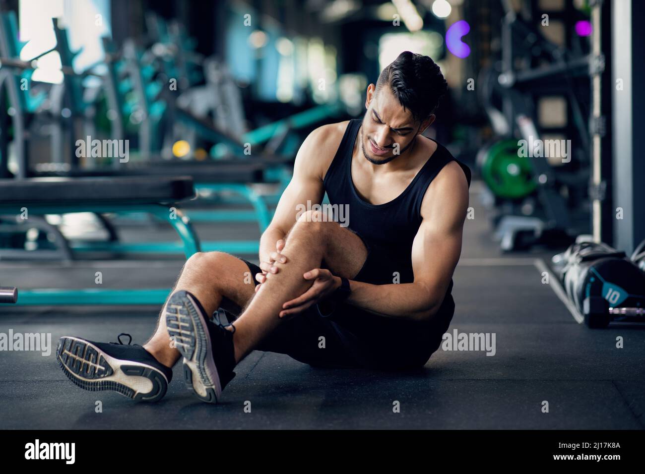 Blessures sportives. Athlète arabe souffrant de traumatisme du genou pendant l'entraînement à la salle de gym Banque D'Images