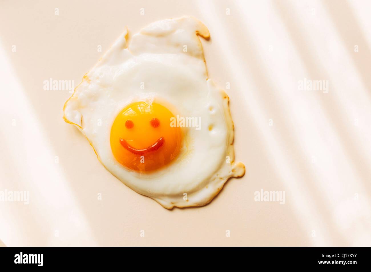 Œuf frit avec un visage souriant sur le jaune Banque D'Images