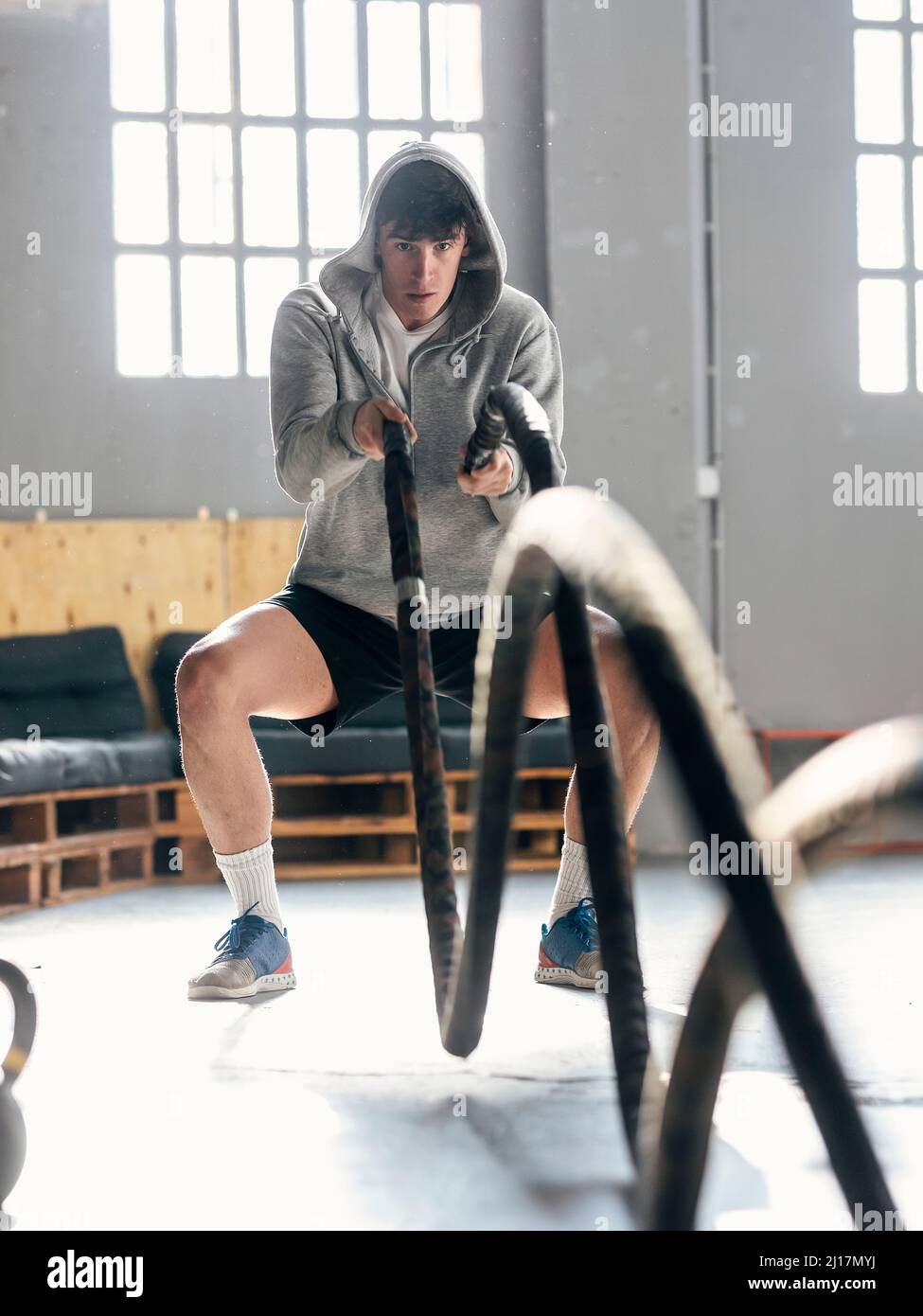 Jeune homme s'entraînant avec des cordes de combat dans la salle de gym Banque D'Images