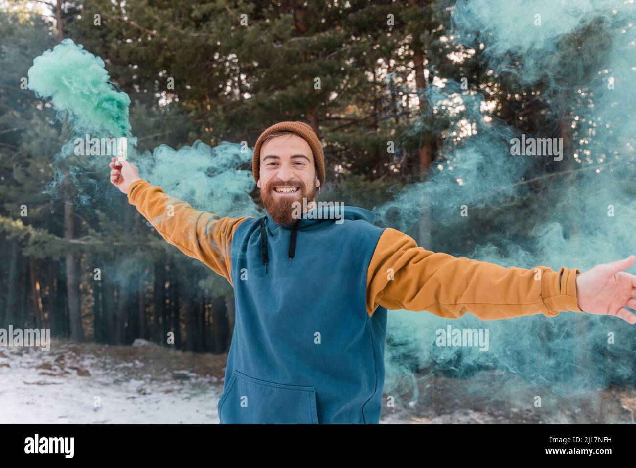 Jeune homme heureux tenant une éruption de détresse bleue dans la forêt Banque D'Images