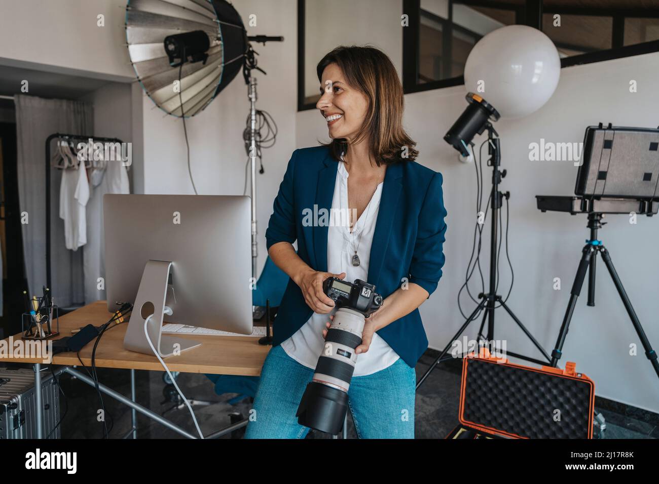 Photographe souriant tenant l'appareil photo en studio Banque D'Images