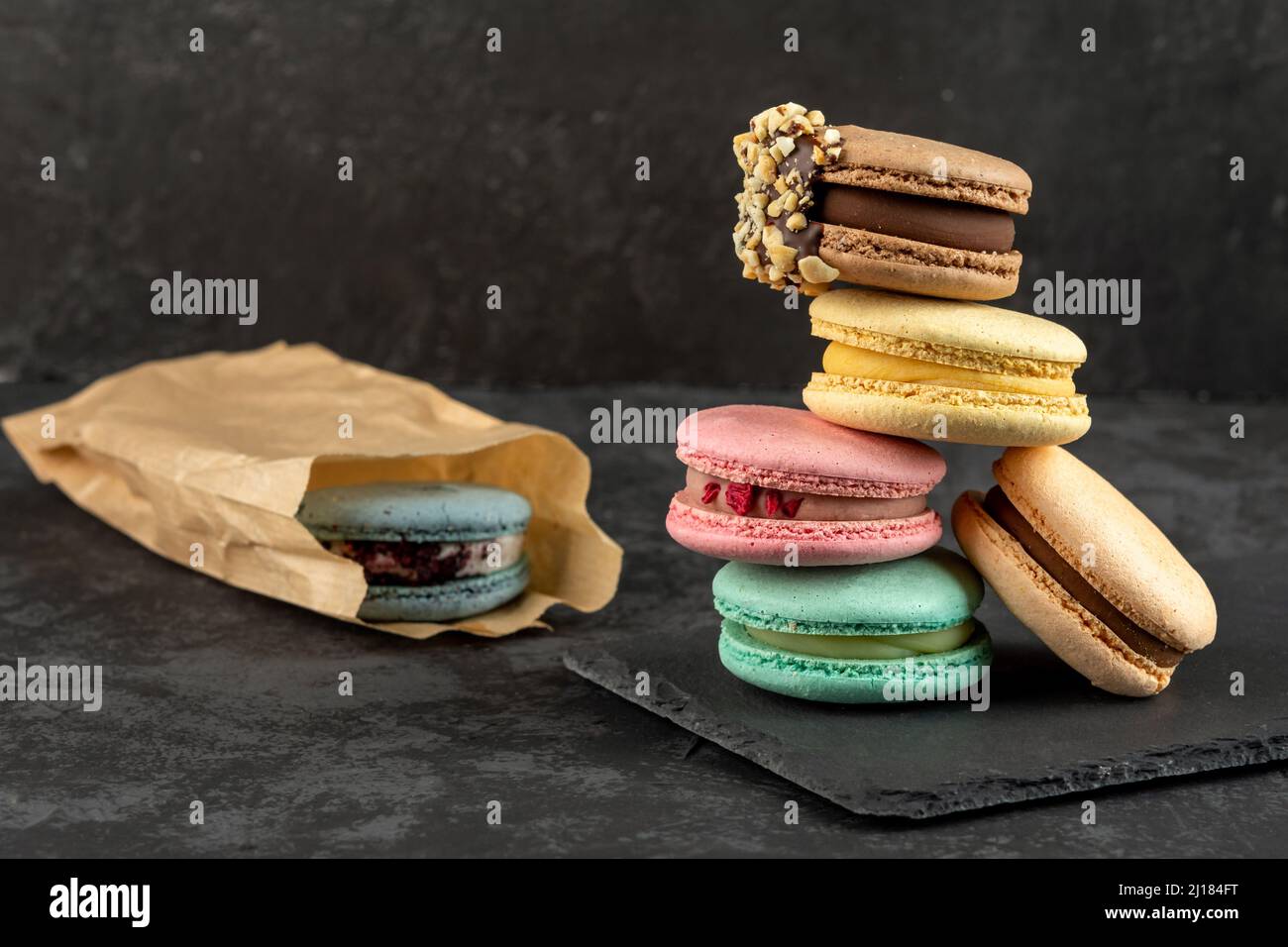 Macarons empilés sur un fond sombre. Délicieux dessert de cuisine française décoré de façon créative sur fond sombre Banque D'Images