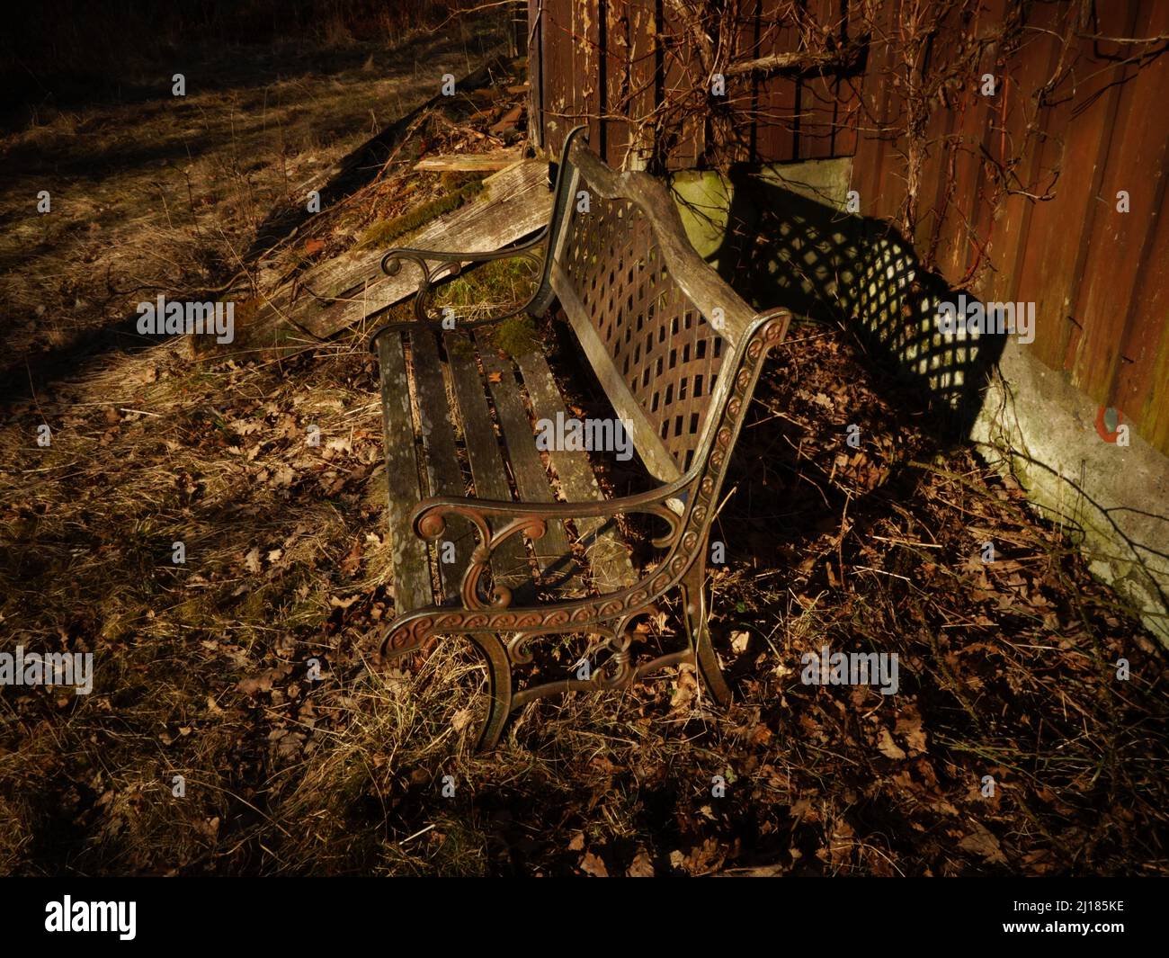 Un ancien banc de jardin en fer forgé vintage avec des détails décoratifs dans le design et un magnifique dossier tressé, un endroit paisible à la campagne. Banque D'Images