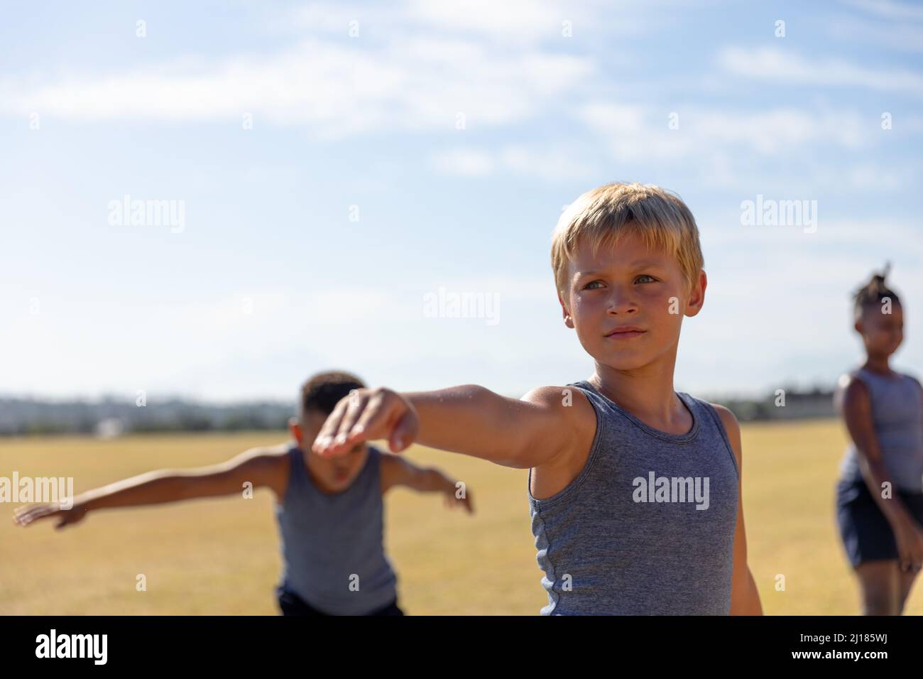 Echoeur élémentaire caucasien avec bras tendu s'exerçant contre le ciel pendant la journée ensoleillée Banque D'Images