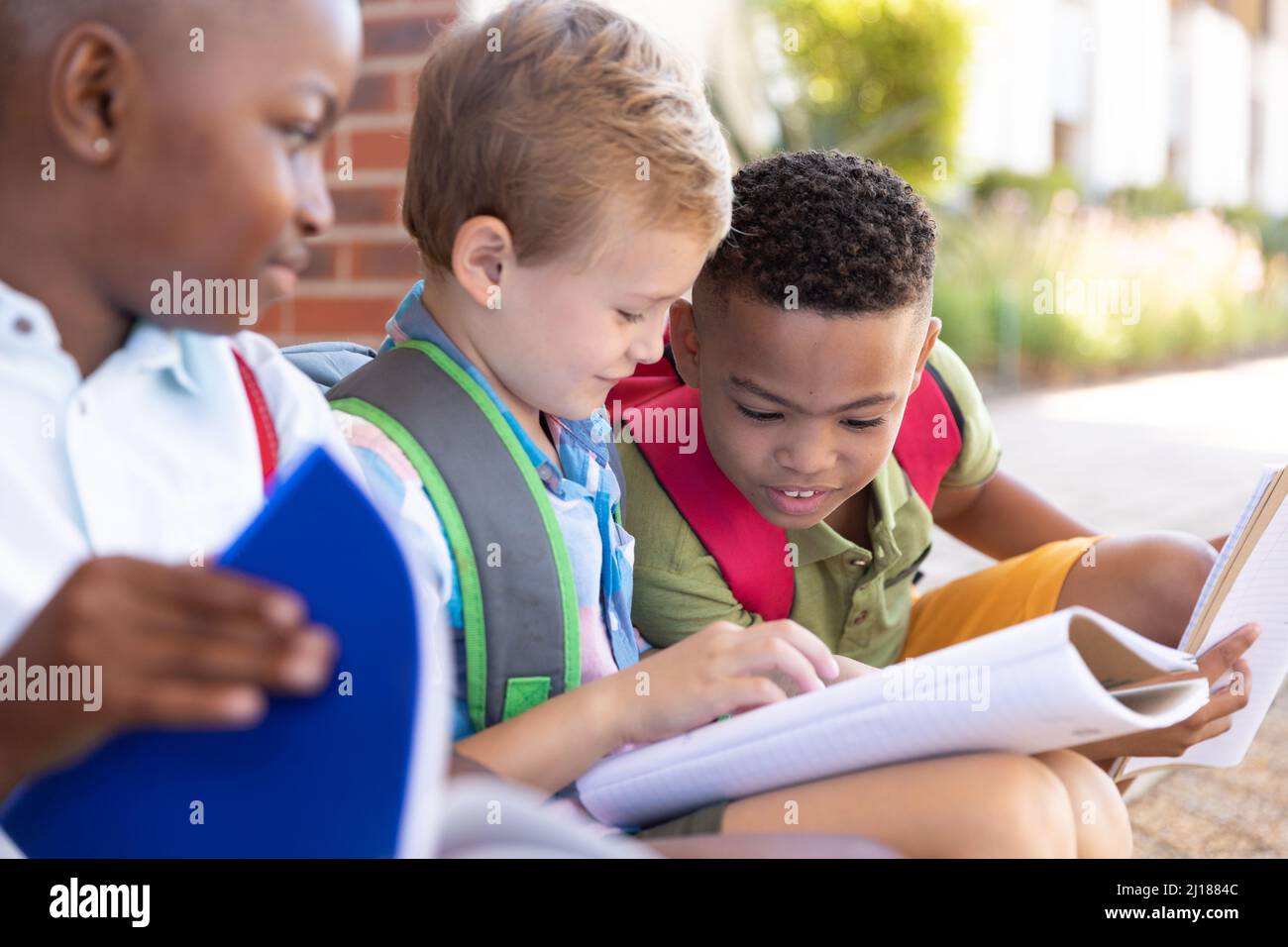 Afro-américain école élémentaire à la recherche de camarades de classe masculins étudiant à l'entrée de l'école Banque D'Images