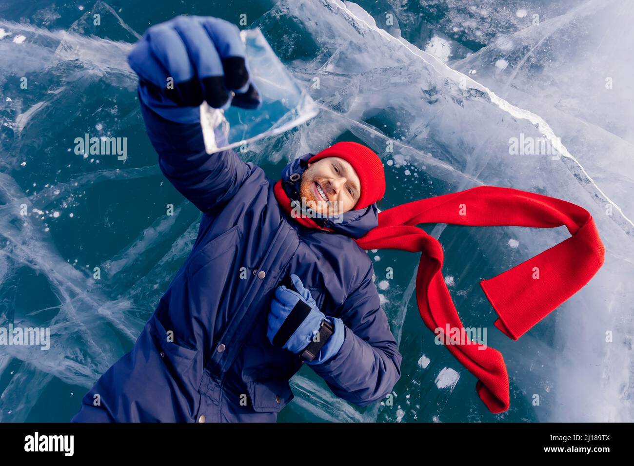 Voyage hiver Lac Baikal, sourire homme touriste dans le chapeau rouge se trouvent sur la glace. Banque D'Images