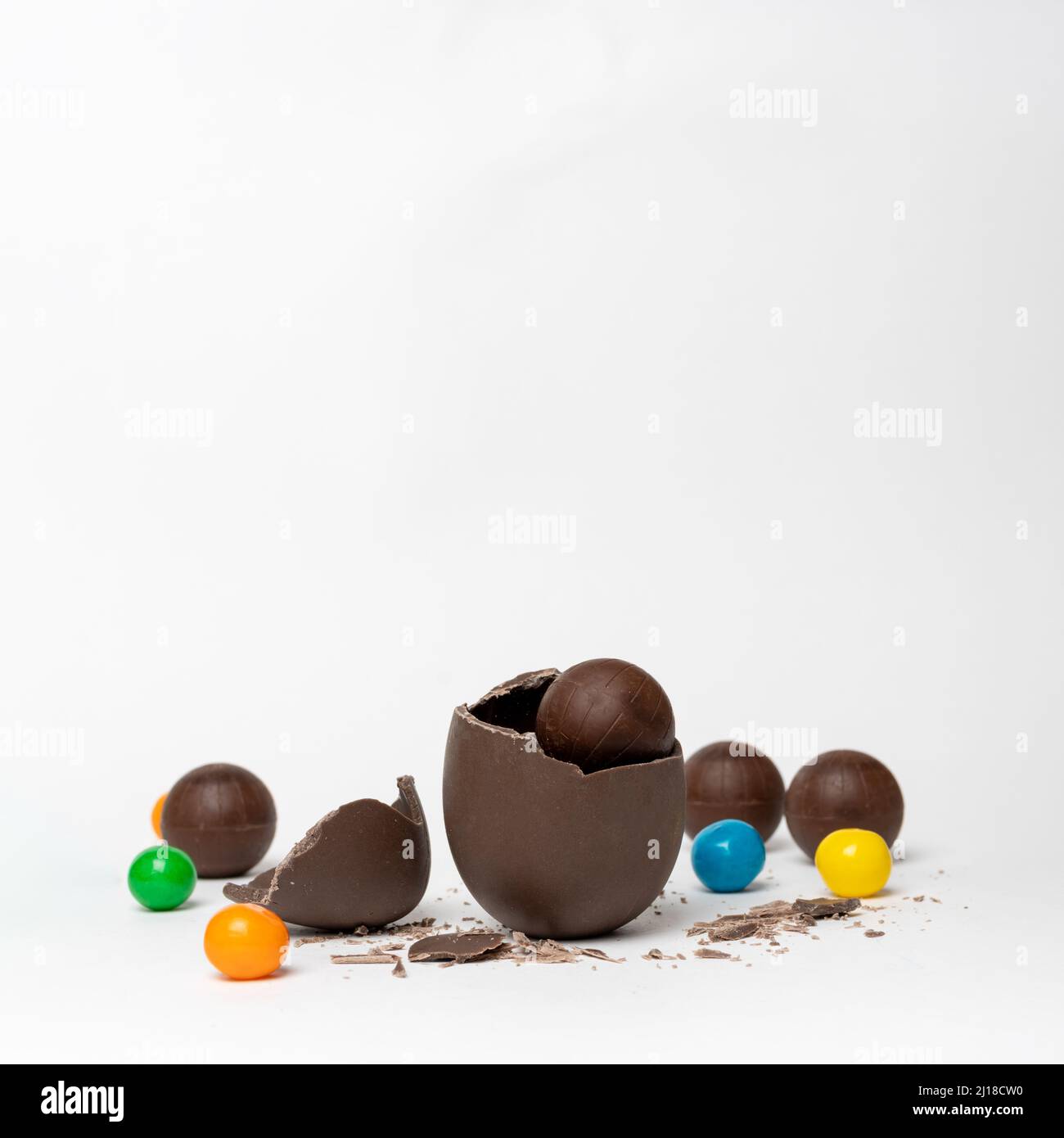 Chocolat craqué oeuf de pâques plein de chocolat de petits bonbons ronds et de bonbons colorés sur fond blanc, espace de copie. Chocolat pour les enfants. EAS Banque D'Images