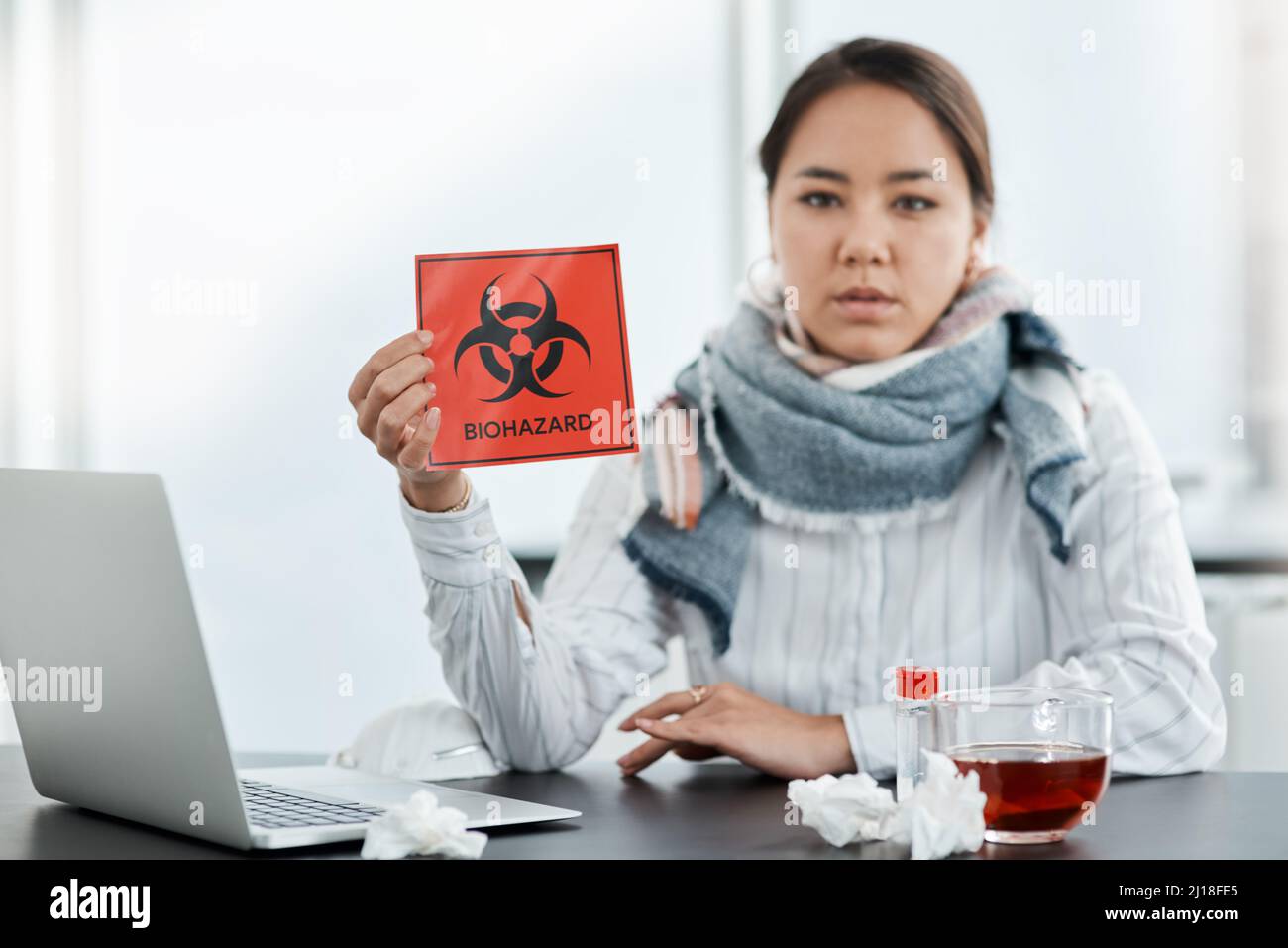 Nous devrions tous être conscients de la sécurité pendant cette crise. Photo d'une jeune femme d'affaires tenant un panneau de danger biologique à son bureau dans un bureau moderne. Banque D'Images