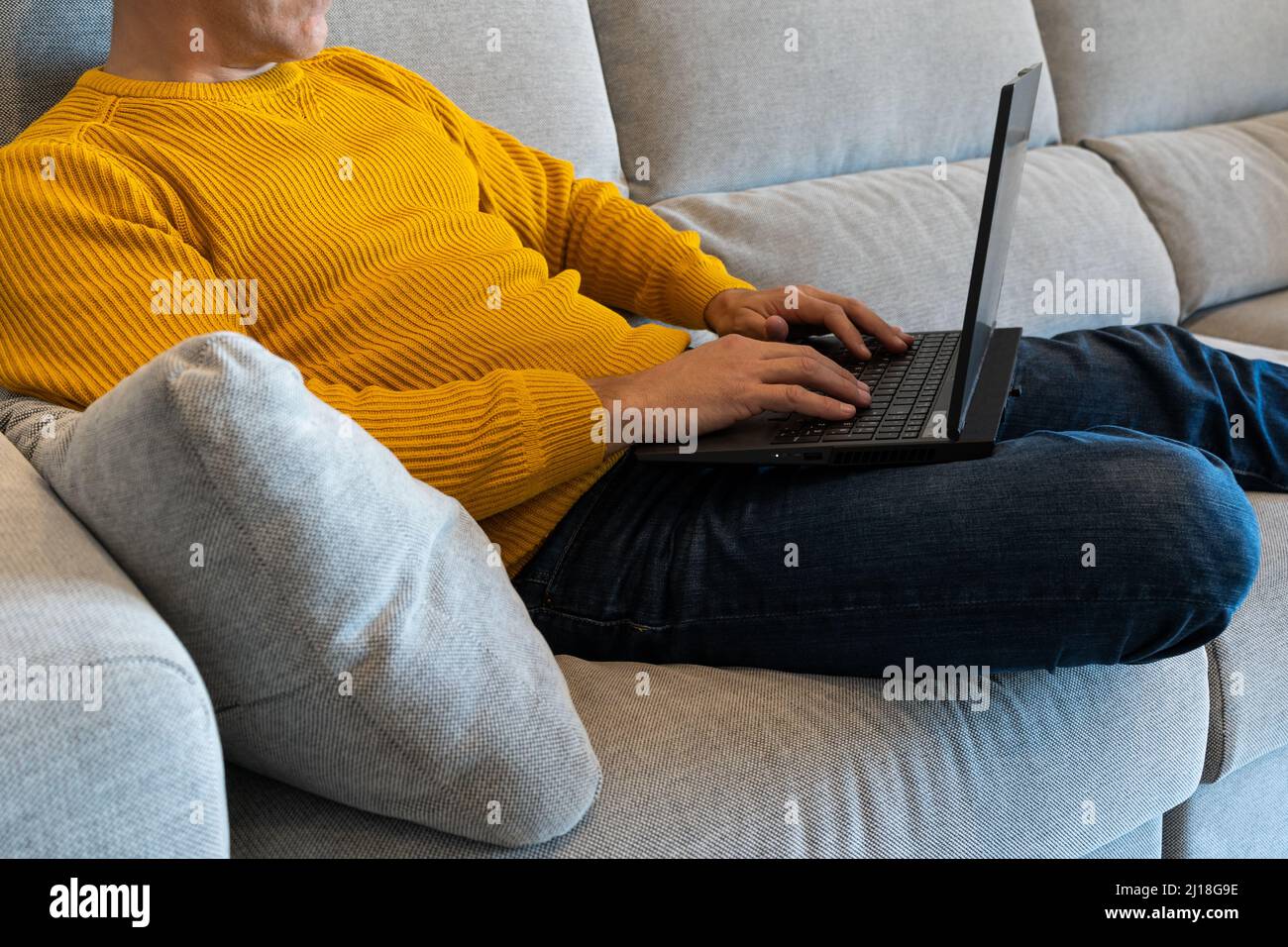 Homme utilisant un ordinateur portable assis sur le canapé. Surfer sur Internet de la maison. Rester à la maison Banque D'Images