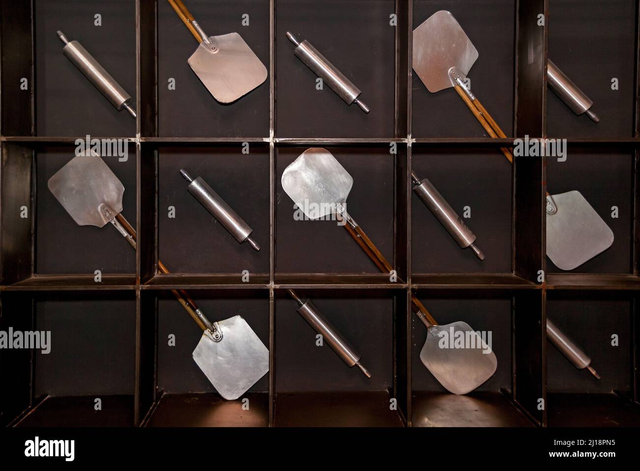 Outil pour la fabrication, l'enlèvement de pizza du four. Le mur sombre sur lequel sont situés les outils pour la pizza Banque D'Images Outil pour la fabrication, l'enlèvement de pizza du four. Le mur sombre sur lequel sont situés les outils pour la pizza Banque D'Images