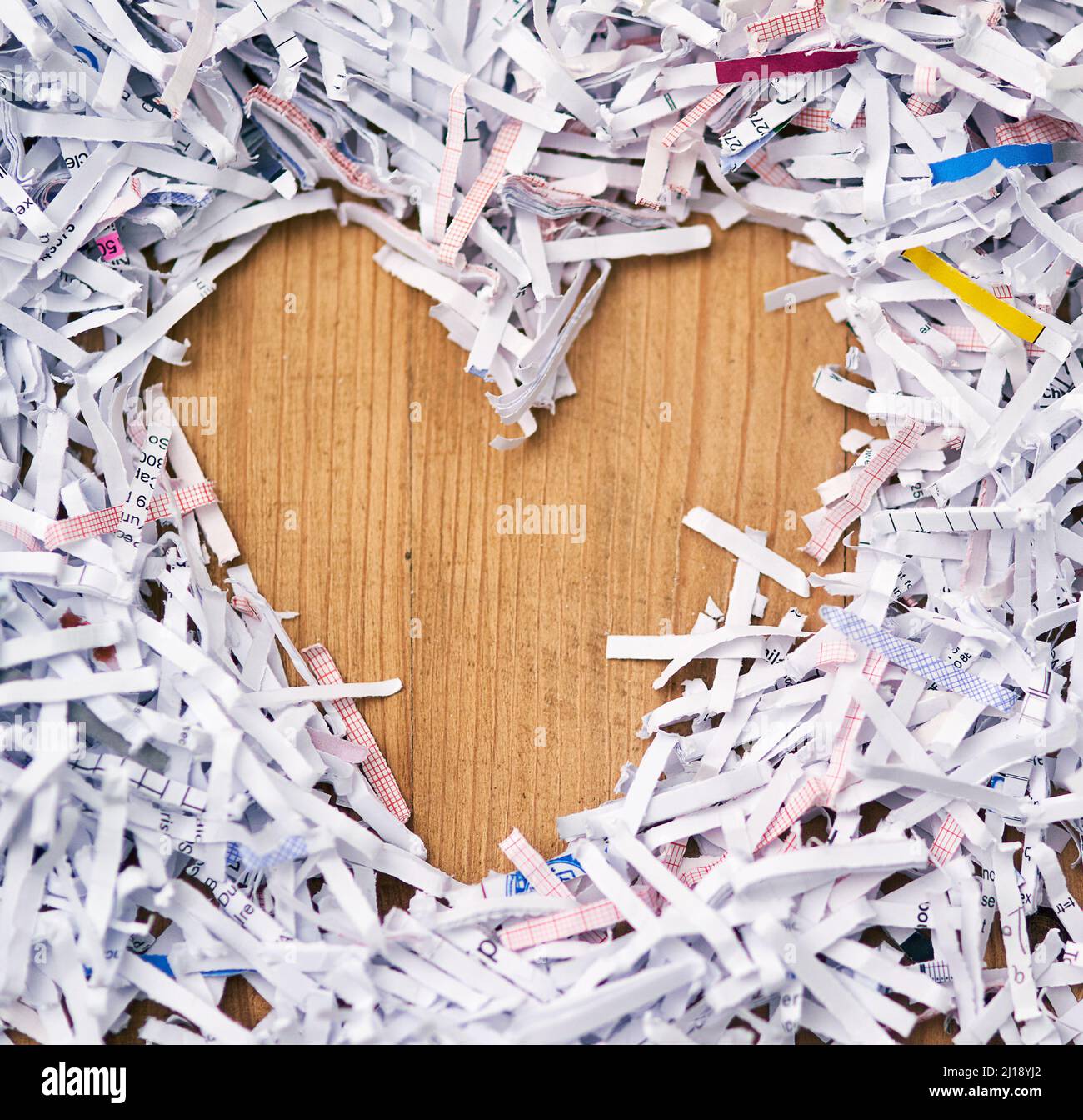 J'adore le papier déchiqueté. Studio photo de papier déchiqueté disposé en forme de coeur sur une table en bois. Banque D'Images