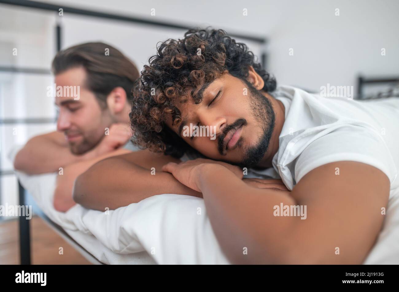 Couple gay biracial dormant dans la chambre Banque D'Images