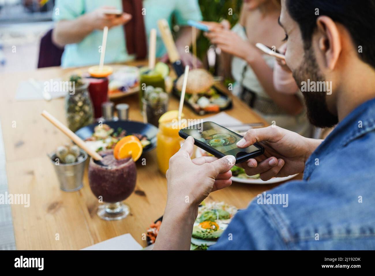 Les jeunes influenceurs s'amusent à faire des vidéos de nourriture saine dans un restaurant branché - concentrez-vous sur la main gauche tenant le téléphone mobile Banque D'Images