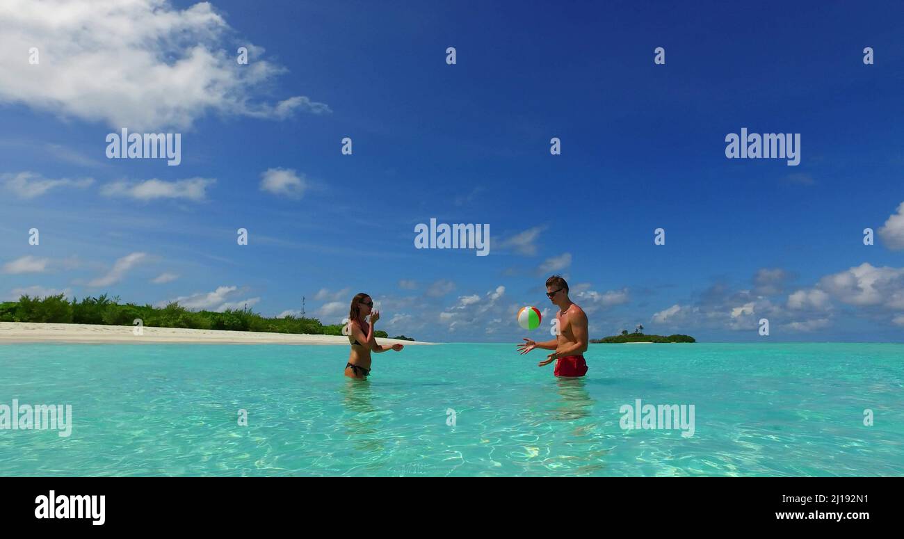 Un couple mignon jouant au ballon dans l'océan à la plage de l'île Rasdhoo, Maldives Banque D'Images