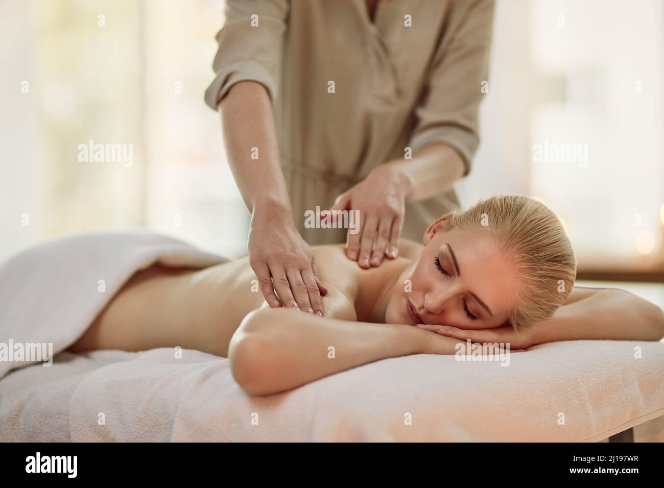Soulager la tension de son corps. Photo courte d'une jeune femme bénéficiant d'un massage du dos au spa. Banque D'Images