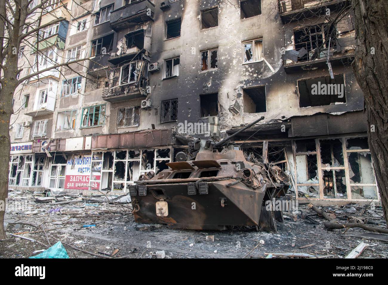 Marioupol, Ukraine. 23rd mars 2022. Un véhicule blindé BTR détruit appartenant probablement aux défenseurs du bataillon Azov se trouve à côté d'un complexe d'appartements détruit dans la ville ukrainienne assiégée. La bataille entre les forces russes et pro-russes et les forces ukrainiennes en déférence, sous la direction du bataillon Azov, se poursuit dans la ville portuaire de Marioupol. Crédit : SOPA Images Limited/Alamy Live News Banque D'Images