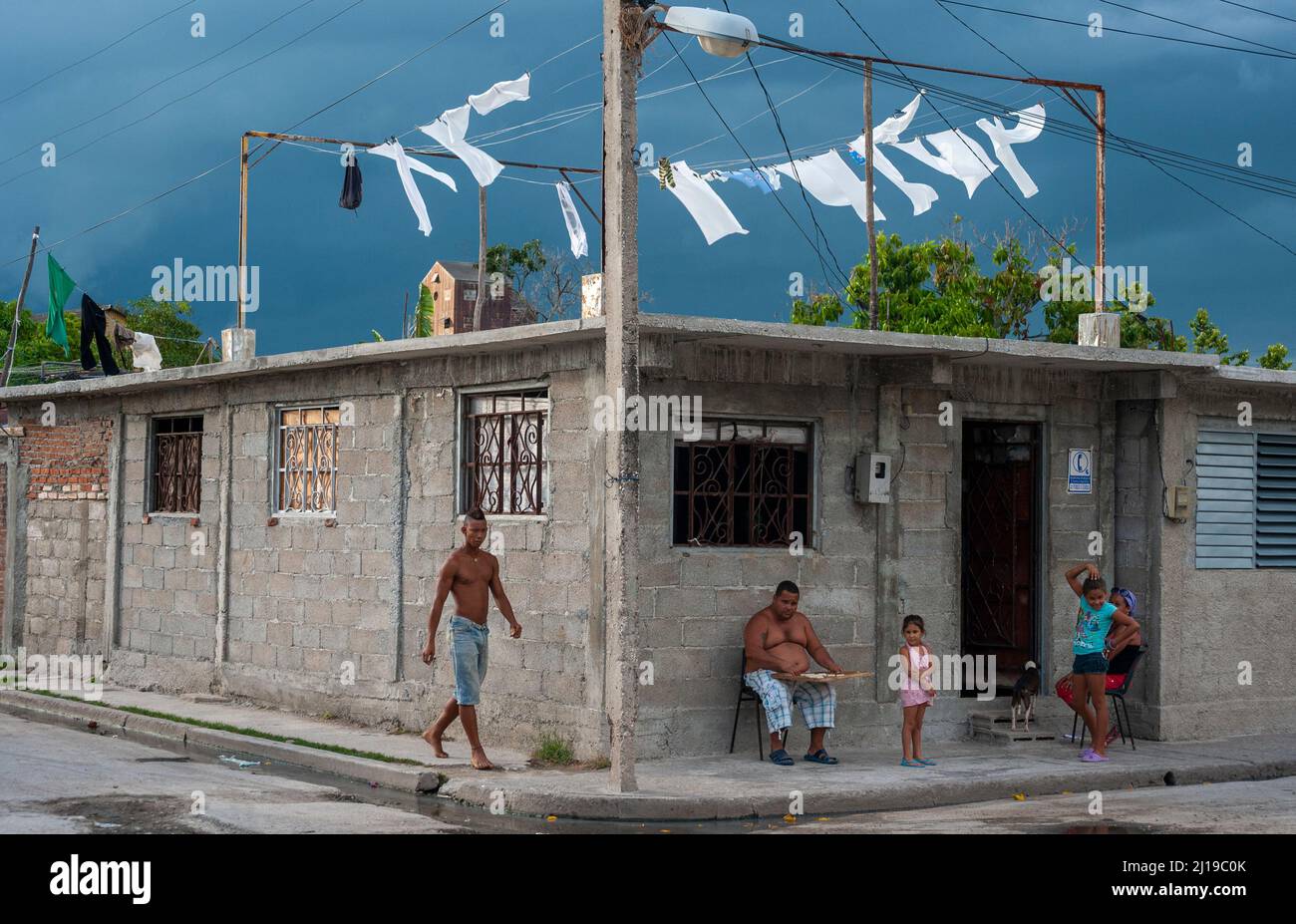 Avant la tempête, une famille et leur chien apprécient la compagnie de l'autre sur la première étape de leur maison à Manzanillo, Cuba. Banque D'Images