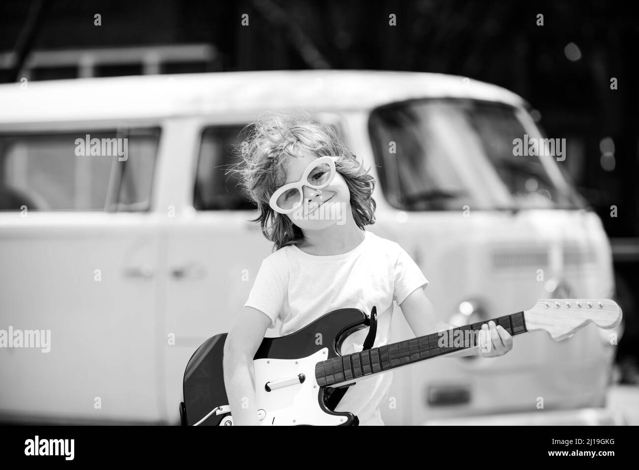 Enfant drôle avec guitare rock. Un petit garçon de campagne américain jouant de la musique. Banque D'Images