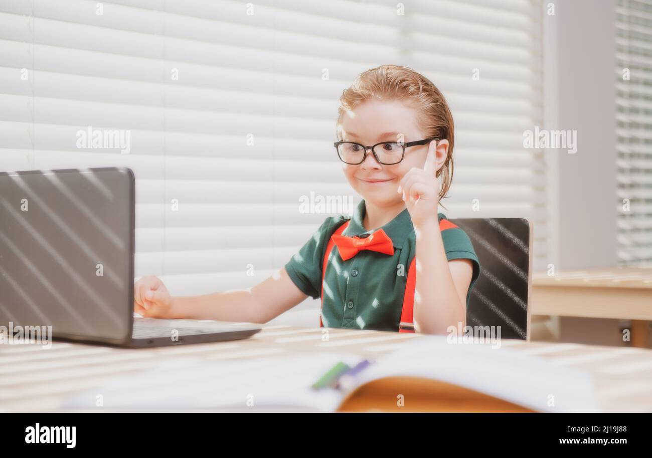 Un jeune garçon à la maison qui écrit ses devoirs. Petit étudiant avec un ordinateur portable prêt à étudier. Enseignement à distance, apprentissage en ligne. Enfant en classe à la maison Banque D'Images
