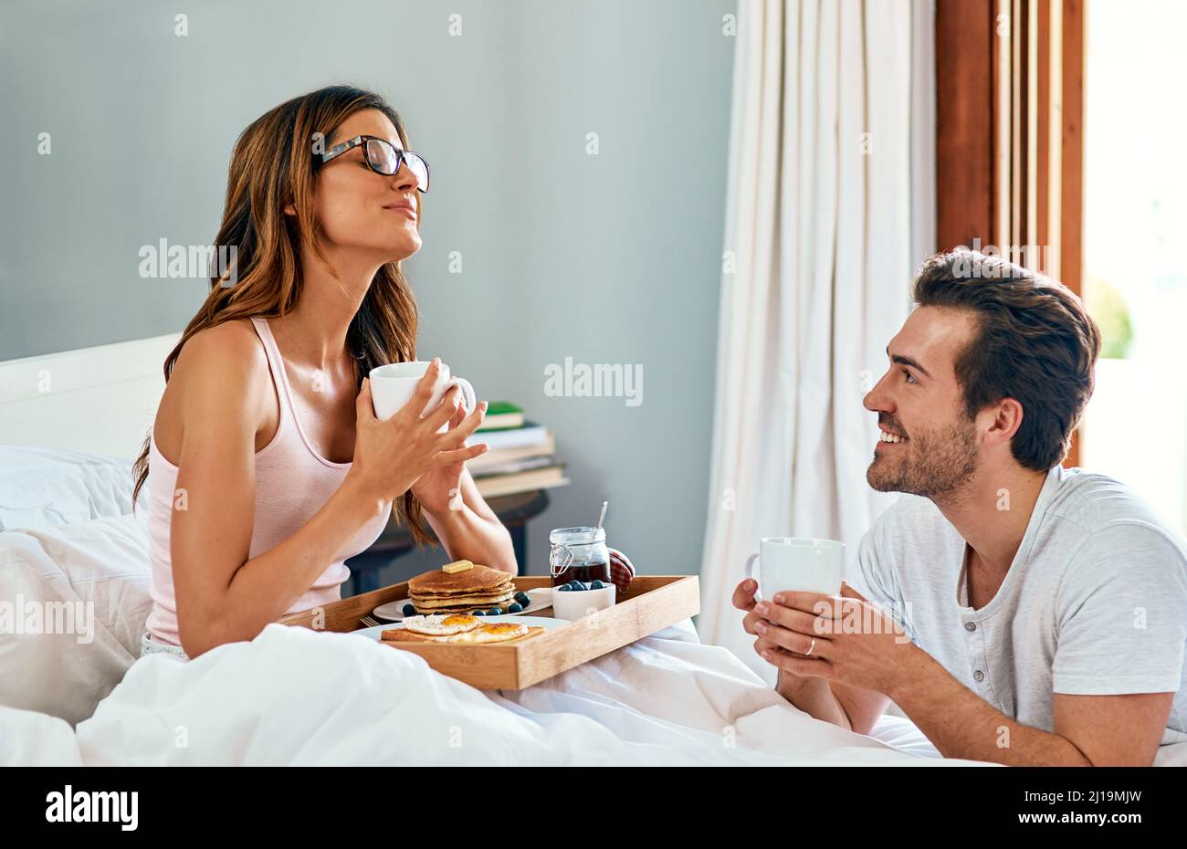 Vous ne savez pas à quel point je suis heureux en ce moment. Photo d'un jeune couple heureux prenant le petit déjeuner au lit ensemble à la maison. Banque D'Images