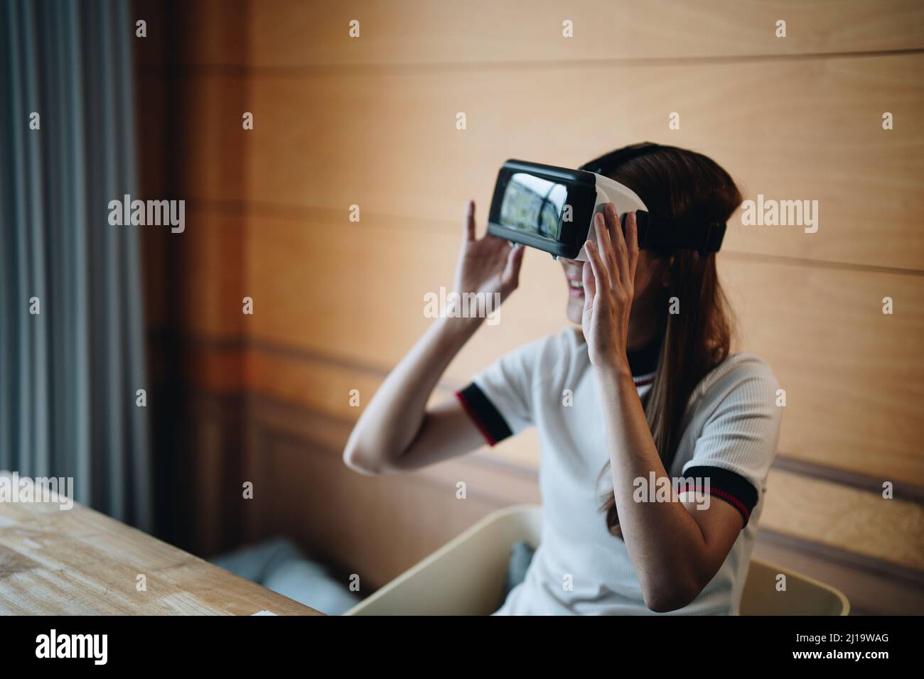 Une jeune femme asiatique pleine de joie porte un micro-casque vr et profite de son temps libre en réalité virtuelle. Femme multiraciale millénaire excitée jouant Banque D'Images
