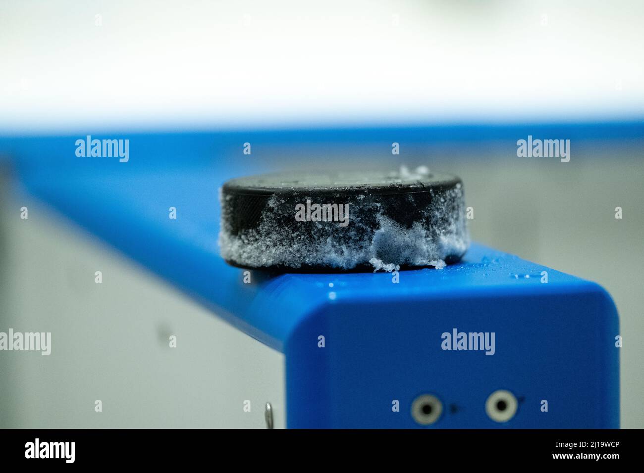 Helsinki / Finlande - 22 MARS 2022 : gros plan d'un palet de hockey sur glace recouvert de neige situé au bord d'une patinoire de hockey sur glace. Banque D'Images