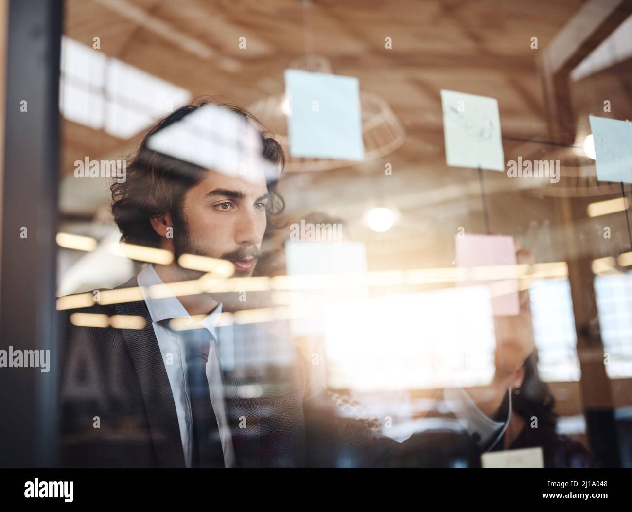 Il a toujours des plans aussi grands. Photo d'un jeune homme d'affaires écrivant des notes sur un mur de verre dans un bureau. Banque D'Images