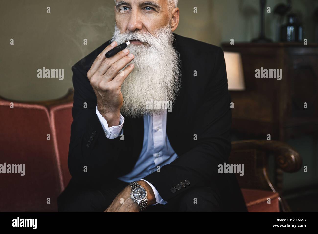 Beau homme âgé fumant système de chauffage du tabac Banque D'Images