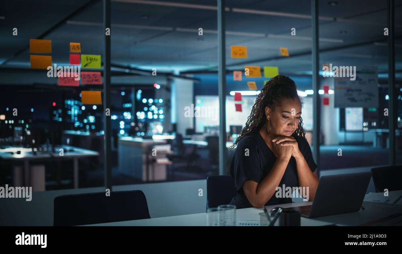Portrait d'une femme d'affaires afro-américaine travaillant sur un ordinateur portable au bureau de Big City tard dans la soirée. Directrice générale féminine de DIGIT Banque D'Images