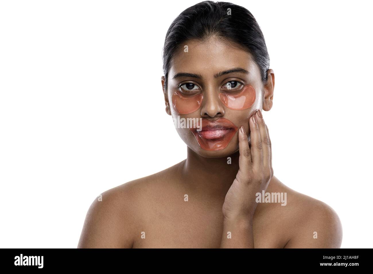 Belle femme indienne avec des timbres hydratants pour les yeux et un masque de lèvre sur son visage Banque D'Images