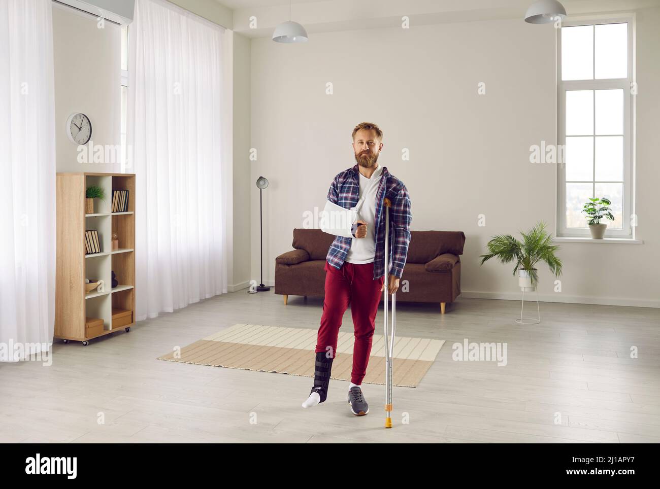 Portrait de l'homme qui a des blessures au bras et à la jambe et porte des bandages spéciaux et s'appuie sur la béquille. Banque D'Images