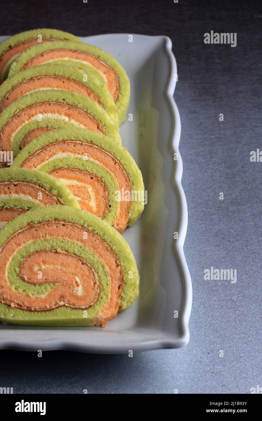 Focus sélectif Bolu Gulung ou gâteau en rouleau de Pandan et fraise à la crème de vanille. Tranché. Servi sur fond blanc, espace de copie Banque D'Images