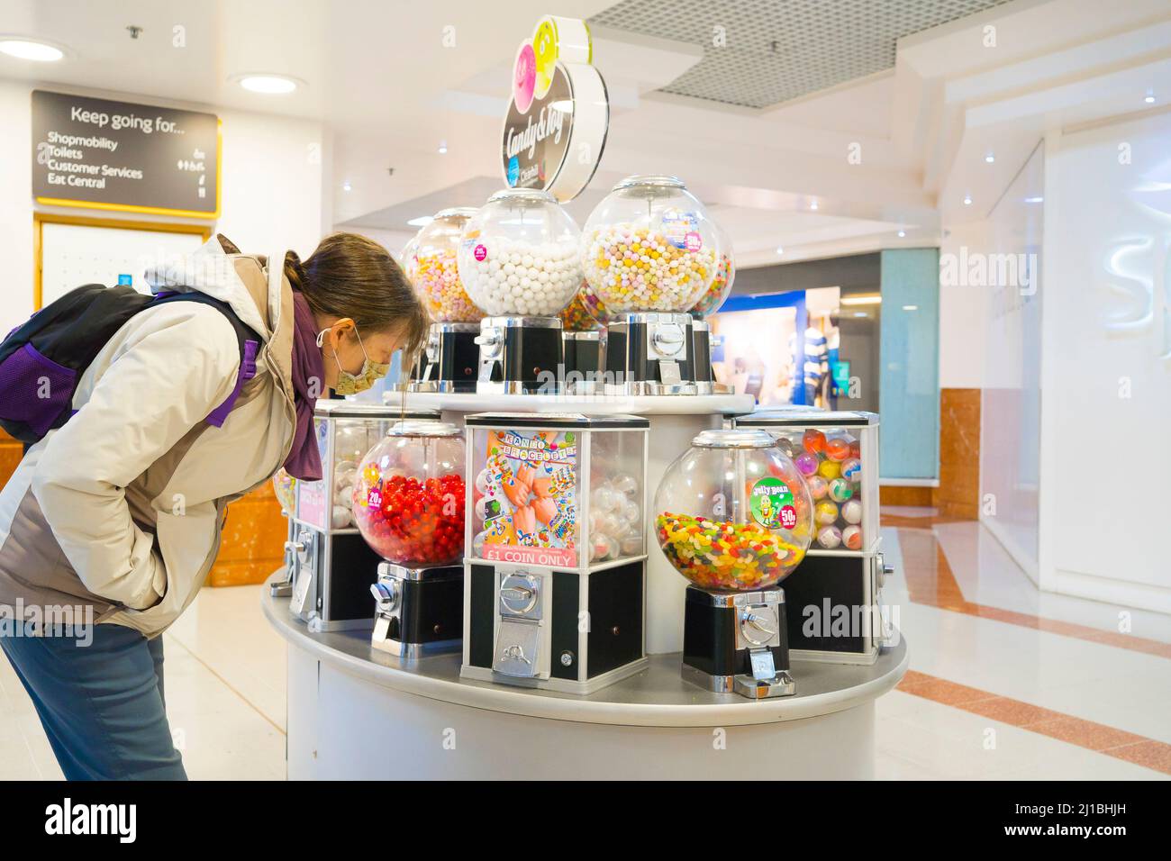 Lady Shopper regardant un stand de bonbons et de jouets dans un centre commercial. Banque D'Images