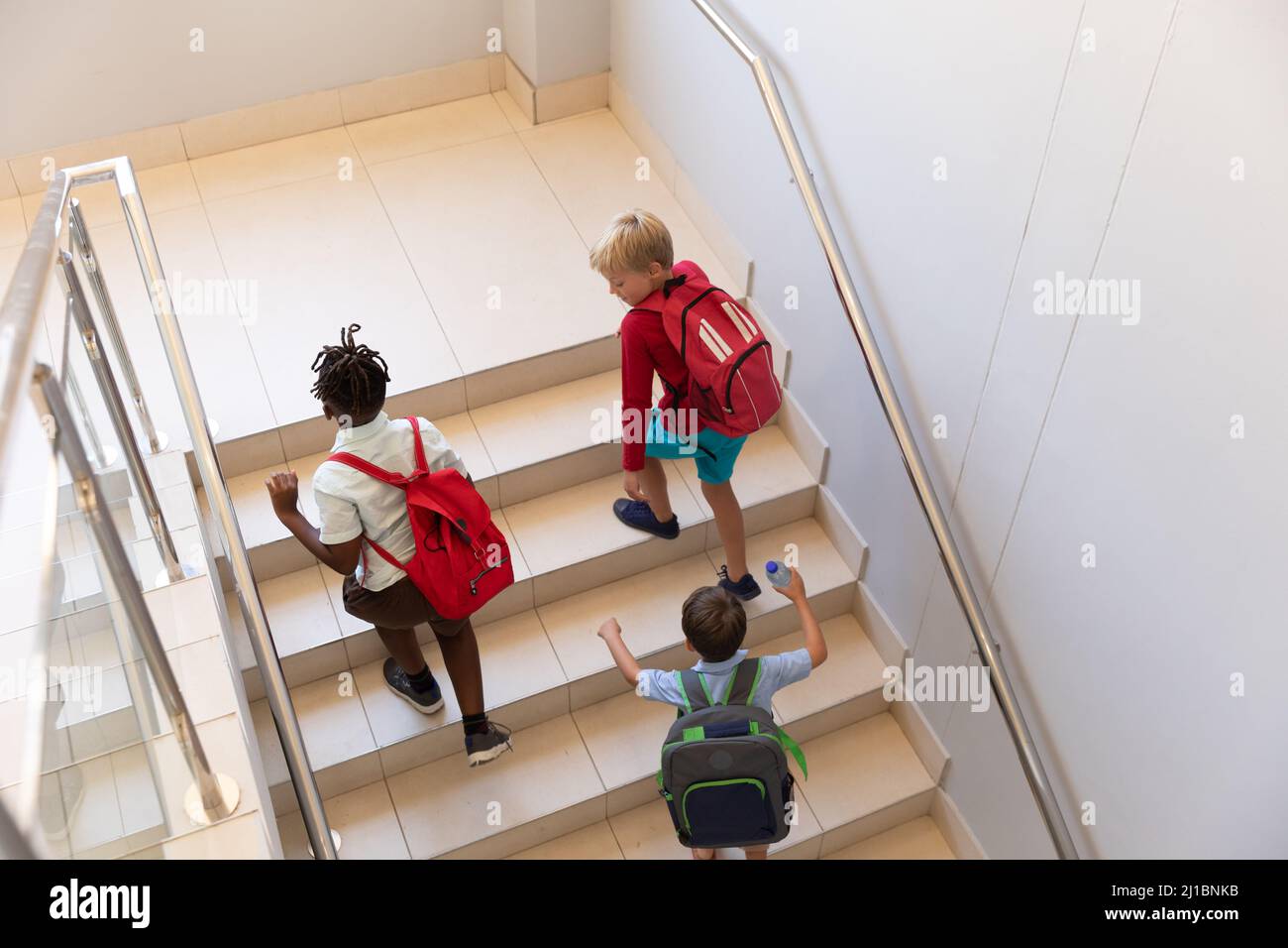 Vue en grand angle des élèves multiraciaux de l'élémentaire avec marche à dos dans le bâtiment de l'école Banque D'Images