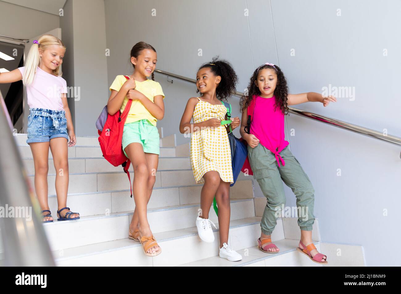 Une longueur complète de filles d'école primaire multiraciale qui se déplacent vers le bas dans la construction de l'école Banque D'Images