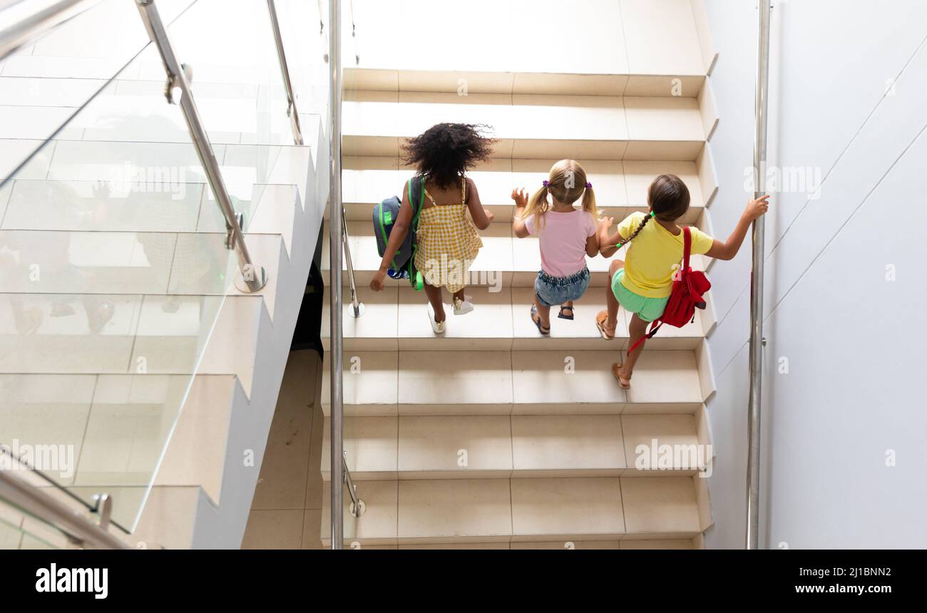 Vue en grand angle des élèves multiraciaux de l'élémentaire grimpant des marches dans le bâtiment de l'école Banque D'Images